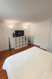 a bedroom with a white bed and a flat screen tv at Appartement T2 à Neuilly in Neuilly-sur-Seine
