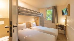 a hotel room with two beds and a window at Premiere Classe Roissy CDG - Paris Nord 2 - Parc des Expositions in Roissy-en-France