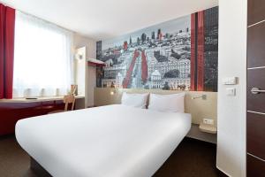 a hotel room with a white bed and a painting on the wall at B&B Hotel Warszawa-Okęcie in Warsaw