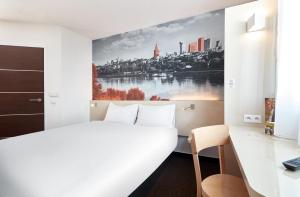 a bedroom with a white bed and a painting on the wall at B&B Hotel Warszawa-Okęcie in Warsaw