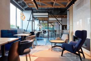 ein Restaurant mit Tischen, Stühlen und Fenstern in der Unterkunft B&B Hotel Warszawa-Okęcie in Warschau