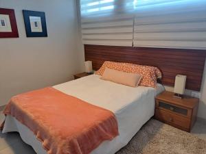 a bedroom with a bed with an orange blanket and a window at Hadeda Cottage in Johannesburg