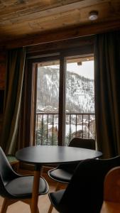 a table and chairs in front of a large window at Résidence GRAND COCOR, Skis aux pieds -Studio 25 m2- by MONTBLANC LOGDE in Val dʼIsère