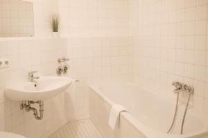 a white bathroom with a sink and a bath tub at SUNNYHOME Monteurwohnungen und Apartments in Weiden in Weiden