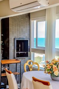 a dining room with a table and chairs and a fireplace at Mar a Lago - Beira Mar Barra Velha - 4 Quartos in Barra Velha