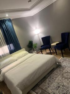 a bedroom with a white bed and two blue chairs at غرفة الجوري 2 الباب الذكي in Dammam
