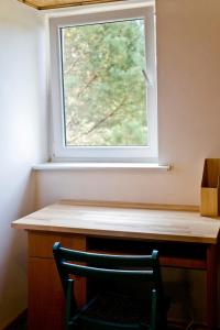 a chair sitting at a desk under a window at Przytulny dom w sosnowym lesie nad rzeką i jeziorem in Rolbik