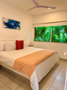 a bedroom with a bed with a red pillow and two windows at Papaya Condo Acapulco Diamante -Solo Adultos in Acapulco