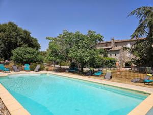 a large swimming pool with chairs and a house at Gîte de caractère tout confort "Au Clos des Ammonites chez Ange&Sébastien " in Labeaume