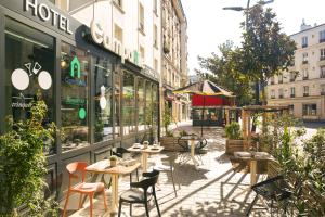 une rue avec des tables et des chaises devant un magasin dans l'établissement CAMPANILE PARIS - Clichy Centre, à Clichy