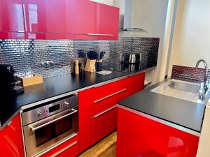 a red kitchen with black counter tops and red cabinets at Superbe 4pers - Saint-mandé, 200m Paris in Saint-Mandé