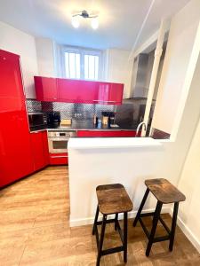 a kitchen with red cabinets and two stools at Superbe 4pers - Saint-mandé, 200m Paris in Saint-Mandé +16 photos