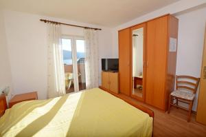a bedroom with a bed and a chair and a television at Apartments Marija in Cres