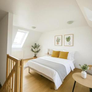 a white bedroom with a large bed with yellow pillows at Aarhus Stay Apartments in Hasselager