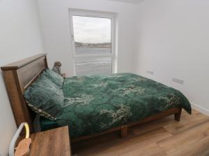 a bedroom with a bed with a green comforter and a window at Lazy Bulldog in Newport-On-Tay