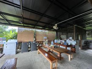 a restaurant with wooden benches and tables in a room at FourTwoEight Pai Resort in Kampong Huaibū