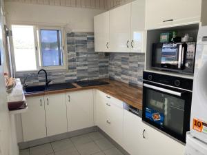 a kitchen with white cabinets and a black microwave at KazParadis les Saintes in Terre-de-Haut