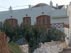 a white house with red windows and a fence at جزيره سهيل in Aswan
