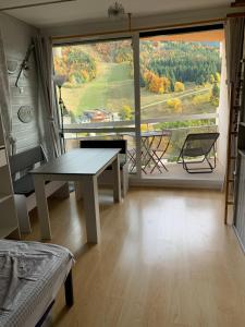 een woonkamer met een tafel en een groot raam bij Avec balcon, au pied des pistes et randos in Villard-de-Lans