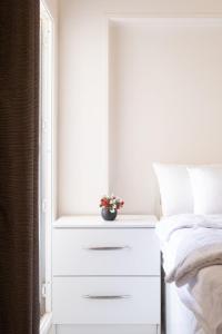 a white dresser with a plant on it next to a bed at luxury house in Cairo