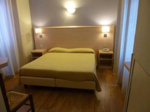 Hotel Da Cesare في ستريزا: غرفة نوم بسرير كبير وطاولتين