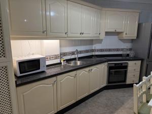 a kitchen with white cabinets and a sink and a microwave at Candelaria Sea Music in Candelaria