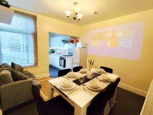 a living room with a table and a kitchen at Peak District Cottage Sleeps 6, Parking and Projectors in all the Rooms in Buxton