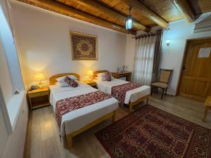 a hotel room with two beds and a rug at Porso Boutique Hotel in Bukhara