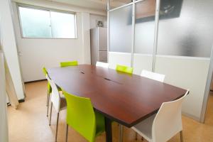 豊山にあるAirport Stay Nagoya Men only guest houseのカンファレンスルーム(木製テーブル、緑の椅子付)