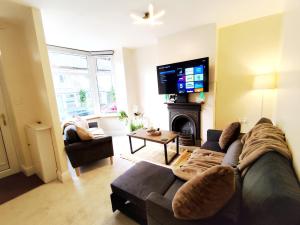 a living room with a couch and a flat screen tv at Peak District Cottage Sleeps 6, Parking and Projectors in all the Rooms in Buxton