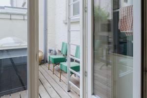 a balcony with green chairs and a glass door at Urban Hideout Just Steps from Antwerp's Highlights in Antwerp
