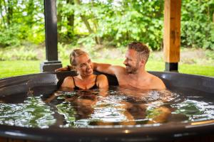 a man and a woman in a hot tub at Natuur Villa met Hottub & Sauna | 2 personen - Resort Valley in Wekerom