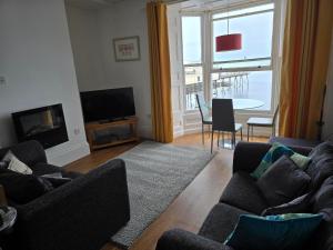a living room with two couches and a large window at Seaview Apartment in Aberystwyth