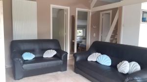 a living room with two black leather chairs and pillows at a l'aise aan zee in Koksijde