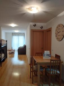 a living room with a table and a clock on the wall at Las torres 1 in Calatayud
