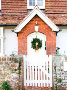 a white fence in front of a white door with a wreath at Cowdray Holiday Cottages in Midhurst
