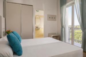 a bedroom with a white bed with a blue pillow at Hotel Caravel B&B in Misano Adriatico +58 photos