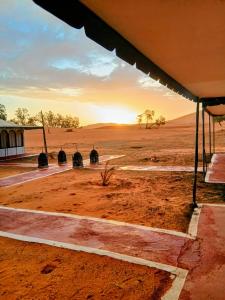 una vista de un desierto con una puesta de sol en el fondo en Luxury white camp, en Merzouga