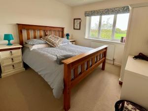 1 dormitorio con cama de madera y ventana en New Forest home - 4-beds and garden - 10 mins from Beach, en Hordle