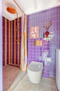 baño con aseo y paredes de azulejos púrpura. en Lila-Licious, en Breda 36 fotos más
