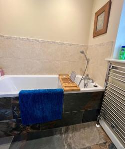 y baño con bañera y toalla azul. en New Forest home - 4-beds and garden - 10 mins from Beach, en Hordle 12 fotos más
