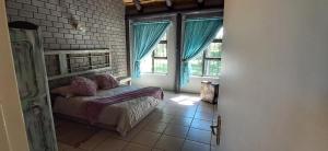 a bedroom with a bed in a room with windows at Daisy Lodge in Barberton