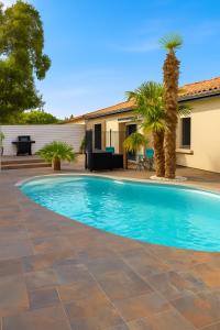 a swimming pool in the backyard of a house with palm trees at Villa détente - Entre terre et mer in Le Gué-dʼAlléré