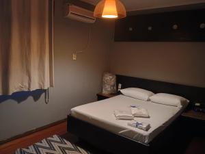 a bedroom with a bed with two towels on it at Motel Antares in Porto Alegre
