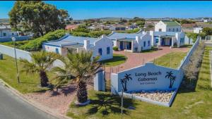 een rij witte huizen met palmbomen en een bord bij Long Beach Cabanas in Langebaan