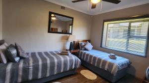 a bedroom with two beds and a mirror and a window at Berlouri Guest House Family Suite in Hekpoort