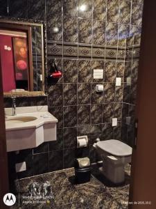 Un baño con lavabo, inodoro y espejo. en Motel Antares, en Porto Alegre