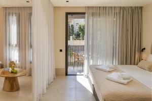 a bedroom with a bed and a balcony at Karteris Luxury Suites in Stalida