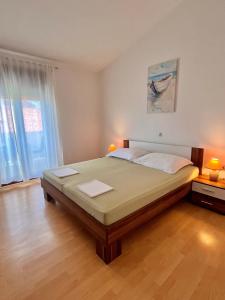 a bedroom with a large bed in a room with wooden floors at Apartmani Fani in Banjol