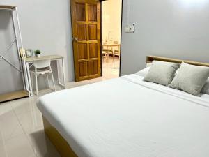 a bedroom with a white bed and a table at I'm Home Narathiwat in Narathiwat